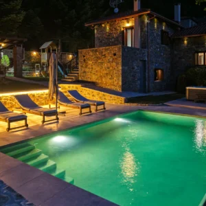 Illuminated pool and stone villa at night at Villa Mainalis