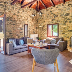 Spacious stone living room with fireplace and doors to the terrace at Villa Mainalis