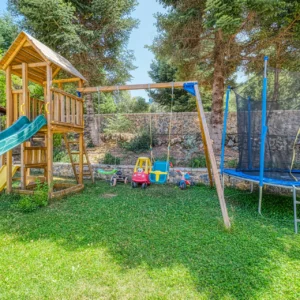 Children's wooden playground and trampoline in the garden at Villa Mainalis