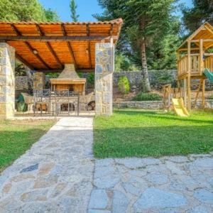 Covered stone barbecue pavilion beside the children's playground at Villa Mainalis