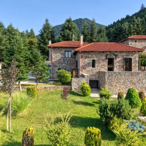 Stone exterior of Villa Mainalis surrounded by landscaped gardens and fir trees