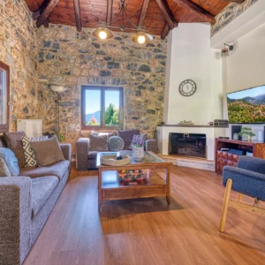 Stone living room with fireplace, television and seating at Villa Mainalis