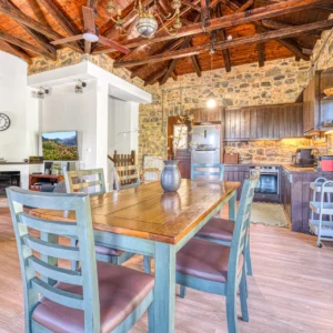 Open-plan dining area and kitchen beneath the timber ceiling at Villa Mainalis