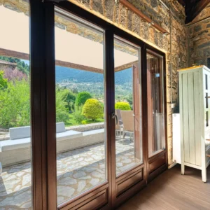 Living area opening through glass doors to the garden and mountains at Villa Mainalis