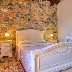 Bedroom 1 with a double bed and exposed stone walls at Villa Mainalis