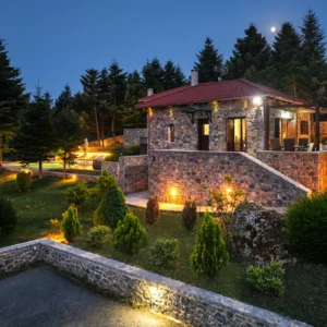 Illuminated stone Villa Mainalis and gardens at night