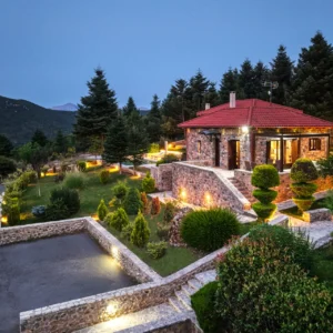 Villa Mainalis illuminated at dusk within the Arcadian mountain landscape
